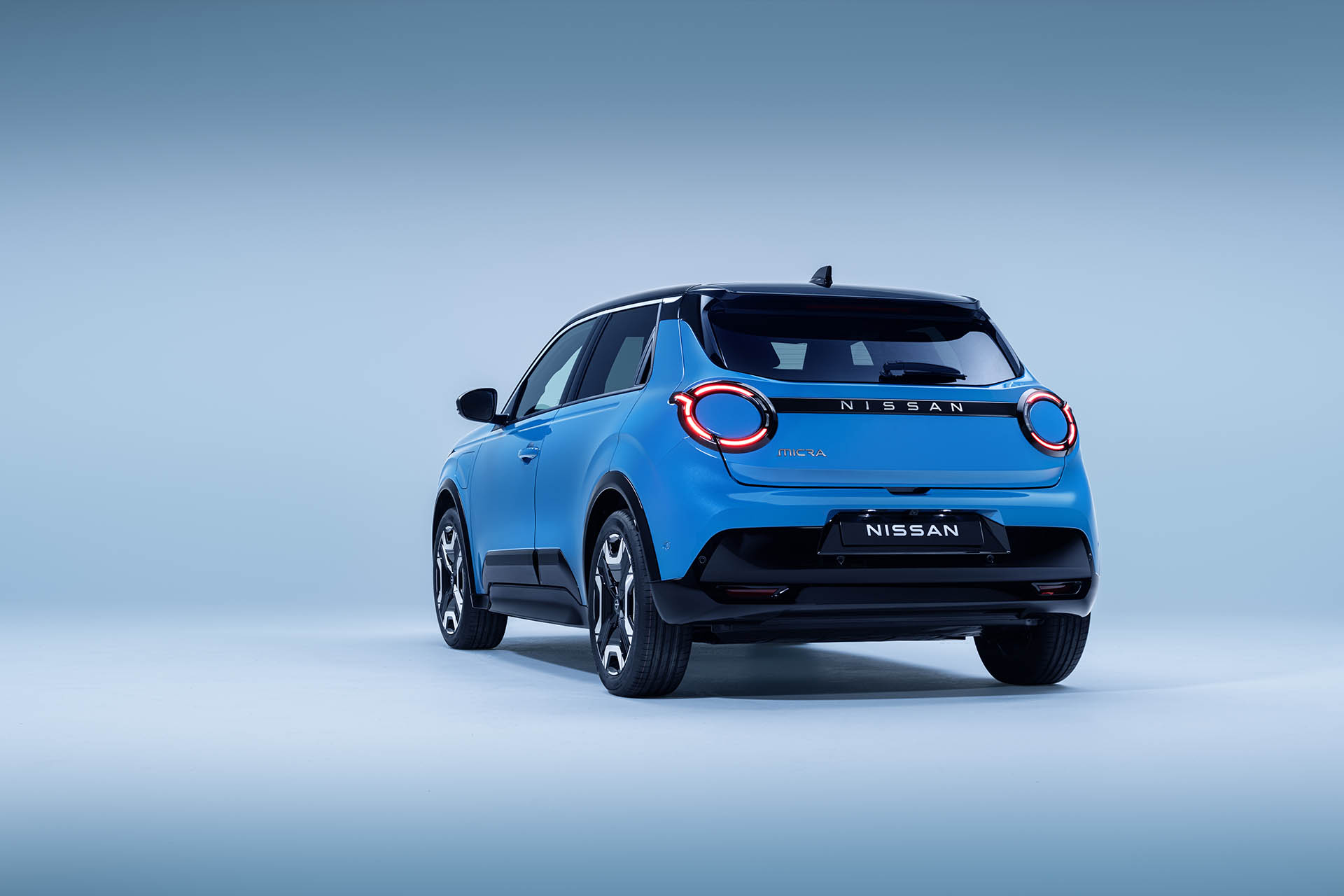 4-view-of-Micra-in-blue-gear-color-showing-signature-lit-headlamps--nissan-name-plate-driver-amp-passenger-doors-wheels-and-black-bumper